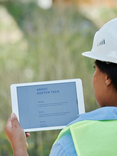 Construction worker in a hard hat reviewing site plans on a tablet